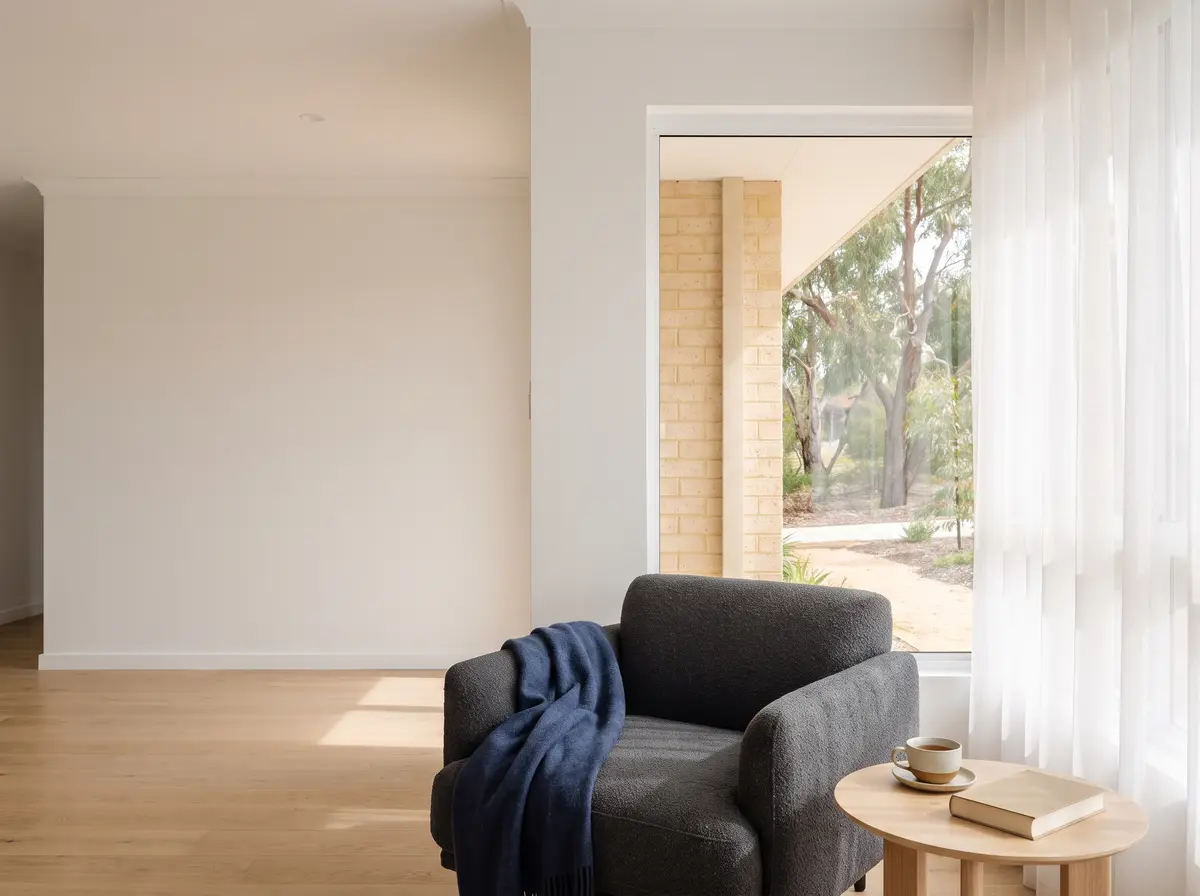 An armchair by a sunny window with a cup of tea and a book